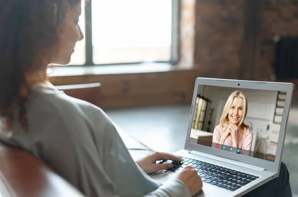 Menina sentada no sofá em casa e conversando on-line com mulher de meia idade — Fotografia de Stock