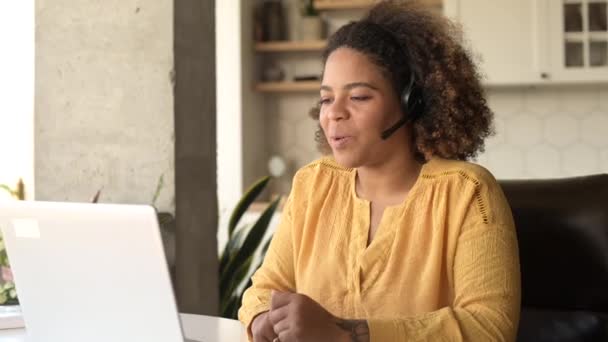 Video görüşmesi için laptop kullanan kablosuz kulaklık takan Afro-Amerikalı bir kadın. — Stok video