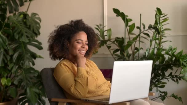 陽気な笑顔アフリカ系アメリカ人の女性が自宅でアームチェアに座って — ストック動画