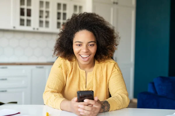 Ung afroamerikansk kvinna använder smartphone hemma — Stockfoto
