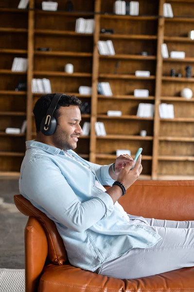 Hombre hipster indio con auriculares sostiene teléfono inteligente —  Fotos de Stock