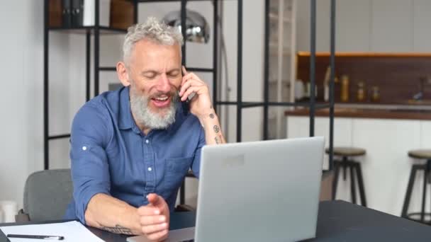Зрелый седой мужчина-предприниматель, использующий ноутбук в домашнем офисе — стоковое видео
