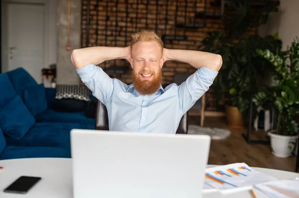 Щасливий бізнесмен тримає руки за голову відпочиває на робочому місці — стокове фото