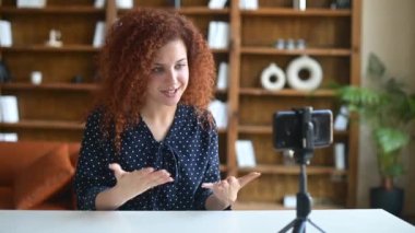 Kıvırcık, çekici bir kadın telefonda kameraya konuşuyor.