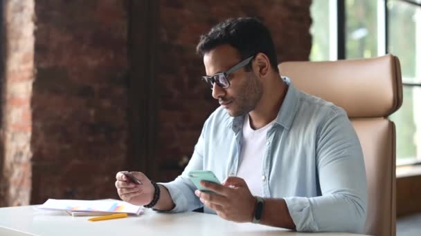 Smilimg indiaanse man met een creditcard en smartphone geld online overmaken — Stockvideo