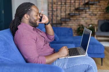 Akıllı Phomne 'da konuşan ve dizüstü bilgisayar kullanan neşeli adam.