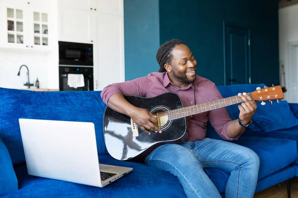 African-American guy playing acoustic guitar and streaming online