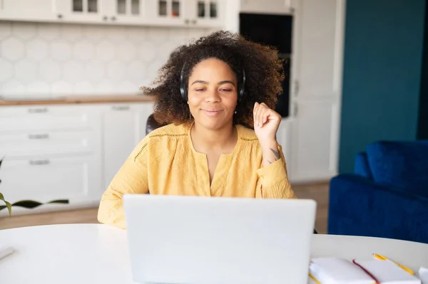 Mujer afroamericana joven que usa auriculares con computadora portátil para trabajo remoto —  Fotos de Stock