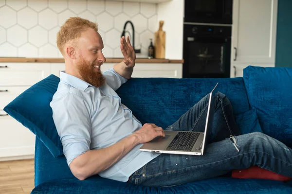 Cheerful carefree red-haired guy using laptop computer for video connection — Stock Photo, Image