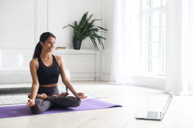 Genç, güzel Hintli kadın evde online derslerle yoga yapıyor.