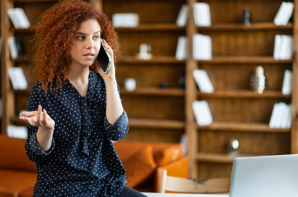 Curly empregado feminino tem conversa telefônica em pé no escritório contemporâneo — Fotografia de Stock