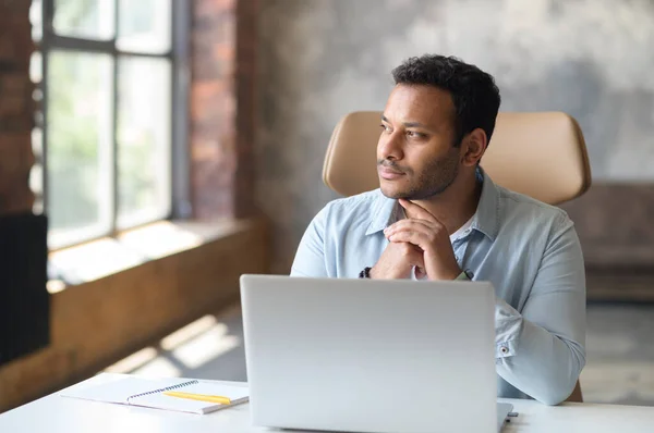 Allvarligt koncentrerad smart indian frilansare kille som använder laptop för att söka — Stockfoto