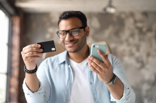 Indiase man in casual kleding en stijlvolle bril met credit card en smartphone — Stockfoto