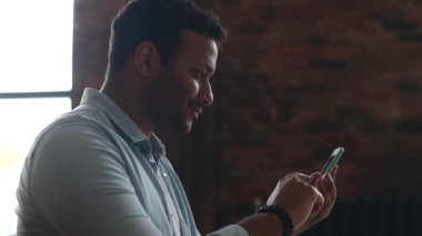 Elinde akıllı bir telefonla gülümseyen neşeli Hintli adam..