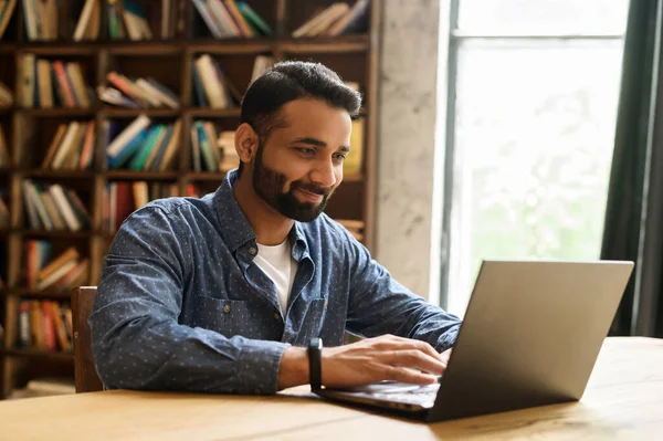 Positiv indisk manlig frilansare tittar på bärbara bildskärmen — Stockfoto