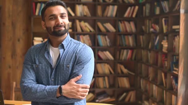 Glimlachende bebaarde Indiase zakenman staat in de buurt van het bureau, kijkt dan weg naar de camer — Stockvideo