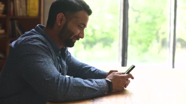 Joven guapo indio freelancer hombre usando smartphone para el chat en línea — Vídeos de Stock