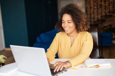 Ev ofisinde dizüstü bilgisayarla çalışan serbest çalışan bir kadın.