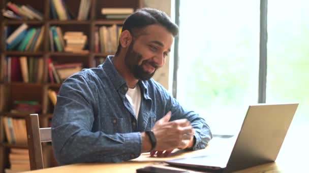 Positivt leende indisk frilansare kille som använder laptop för virtuellt möte på kontoret — Stockvideo
