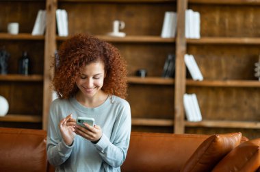 Neşeli, genç, kızıl saçlı kıvırcık kadın internette sohbet etmekten hoşlanıyor.