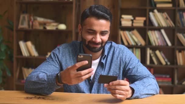 Förvirrad och besviken indisk man använder smartphone och bankkort för shopping — Stockvideo