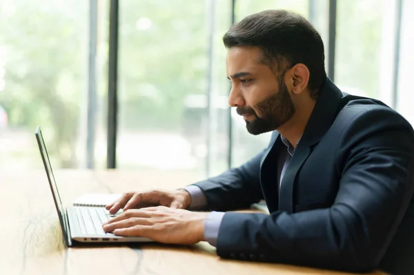 Självsäker modern indisk affärsman i smart casual kostym tittar på datorskärmen — Stockfoto