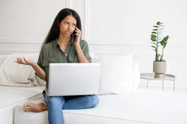 Indian woman talking on the phone while sitting on the sofa at home — Stock Photo, Image