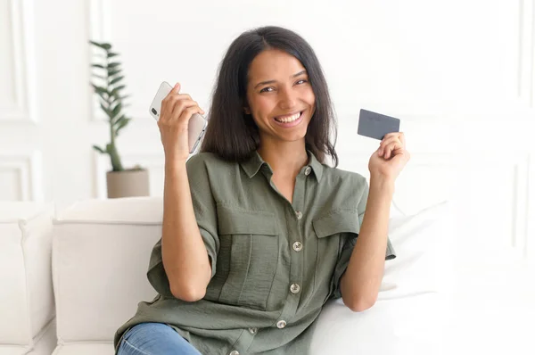 Indiase vrouw het maken van een bestelling online, houdt een smartphone en een pinpas — Stockfoto