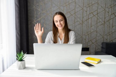 Gülümseyen genç kadın video bağlantısı için bilgisayar uygulaması kullanıyor