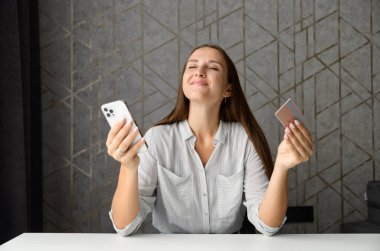 Kredi kartı ve akıllı telefondan ilham almış bir kadın uzun zamandır beklenen alımları hayal ediyor.
