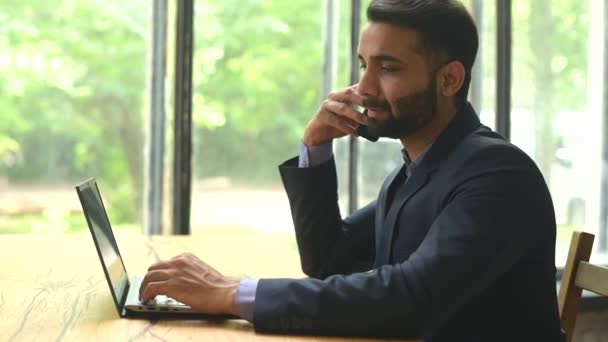 Уверенный индийский бизнесмен в официальном костюме, использующий ноутбук для работы — стоковое видео
