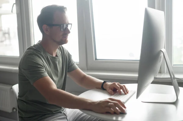 Freelancer guy enjoying working from home, typing messages, answering emails