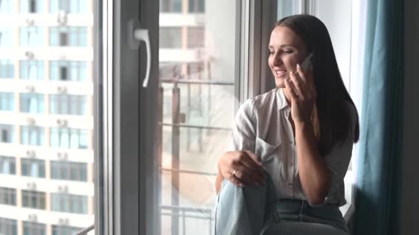Sorridente giovane donna che chiacchiera con un amico sul cellulare — Video Stock