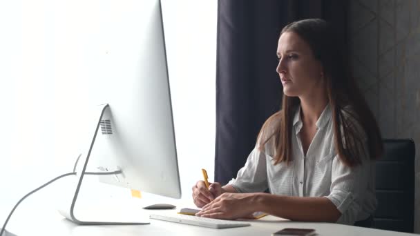 Estudante focada sentada na mesa e escrevendo, fazendo curso educacional on-line — Vídeo de Stock