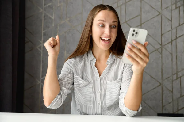 Happy woman holding smartphone with amazed facial expression — Stock Photo, Image