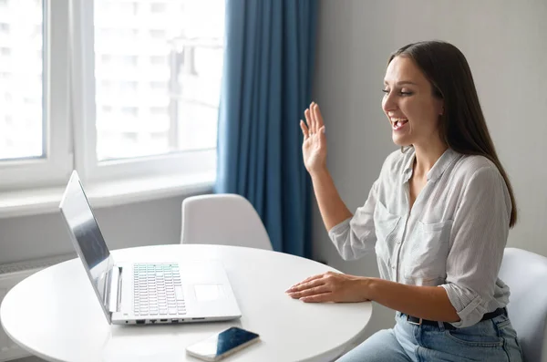 Studentin nimmt an virtueller Konferenz teil, lächelnde Frau winkt in Laptop — Stockfoto