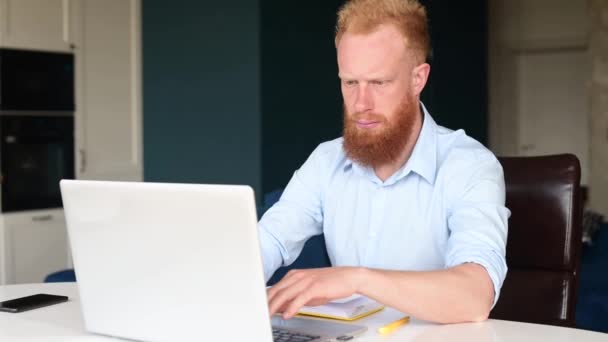 Imeytyy ja huomaavainen punatukkainen liikemies tuijottaa tietokoneen näyttö — kuvapankkivideo