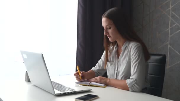 Fokuserad kvinnlig student studerar på distans, med hjälp av laptop för att titta på föreläsningar — Stockvideo