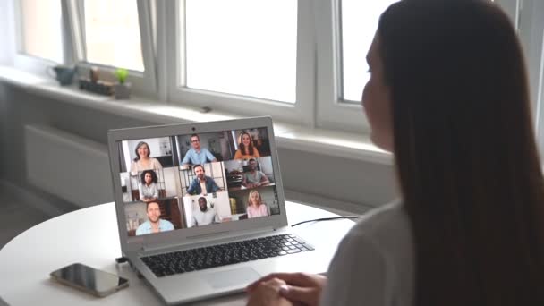 Vista posterior sobre el hombro de una mujer en una pantalla portátil con un equipo diverso — Vídeos de Stock