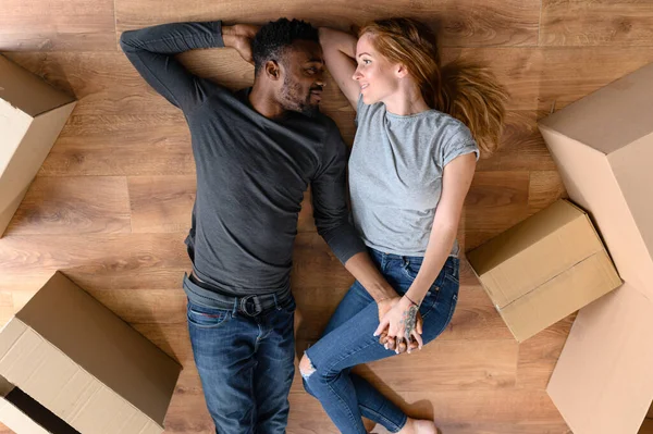 Gelukkig Afrikaans vriendje en charmant Kaukasisch vriendin ligt op de vloer — Stockfoto