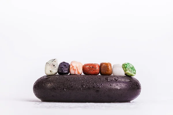 Rândul de chakra cristale pe fierbinte masaj pietre negre — Fotografie, imagine de stoc