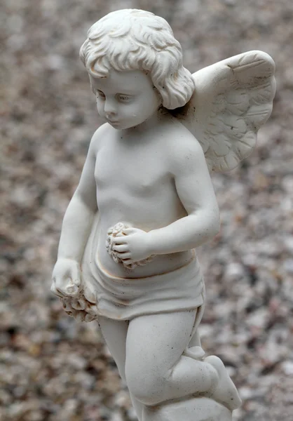 Pequeno anjo ajoelhado com guirlandas de flores — Fotografia de Stock