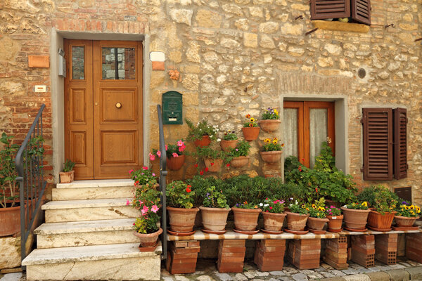 Doorway to the tuscan house with lots of flowerpots, Italy
