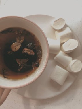 Fincanda bitki çayı ve çay tabağında beyaz bir sufle var.