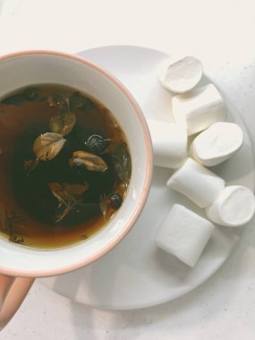 Fincanda bitki çayı ve çay tabağında beyaz bir sufle var.