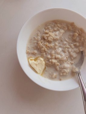 Kahvaltı için bir tabak yulaf lapası ve kalp şeklinde tereyağı. yemek fotoğrafı