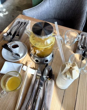 Restoran masa servisi yapıyor, tabaklar ve çatal bıçak takımı hazır. Masada meyve çayı ve milkshake var. yemek fotoğrafı.