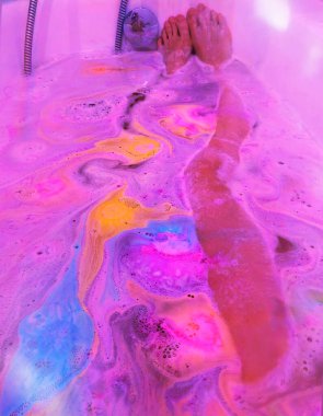 waman güzel renkli suda banyo yapar, bir banyo bombasıyla, parlak su renkleriyle pembe, mor, mavi, kırmızı, sarı
