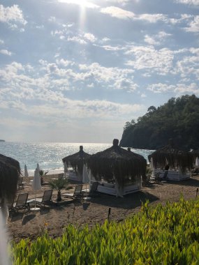 Şık, güzel bir manzara tasarımı. Güzel sahil, beyaz bulutlar, deniz, kum, yazlık evler. Seyahat tatili kavramı