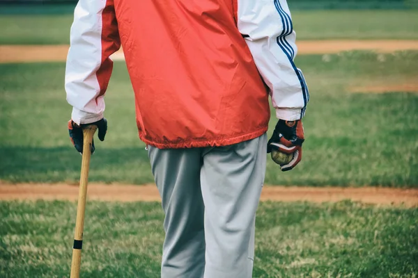Beyzbol koçu topu tutuyor ve maçı izliyor.